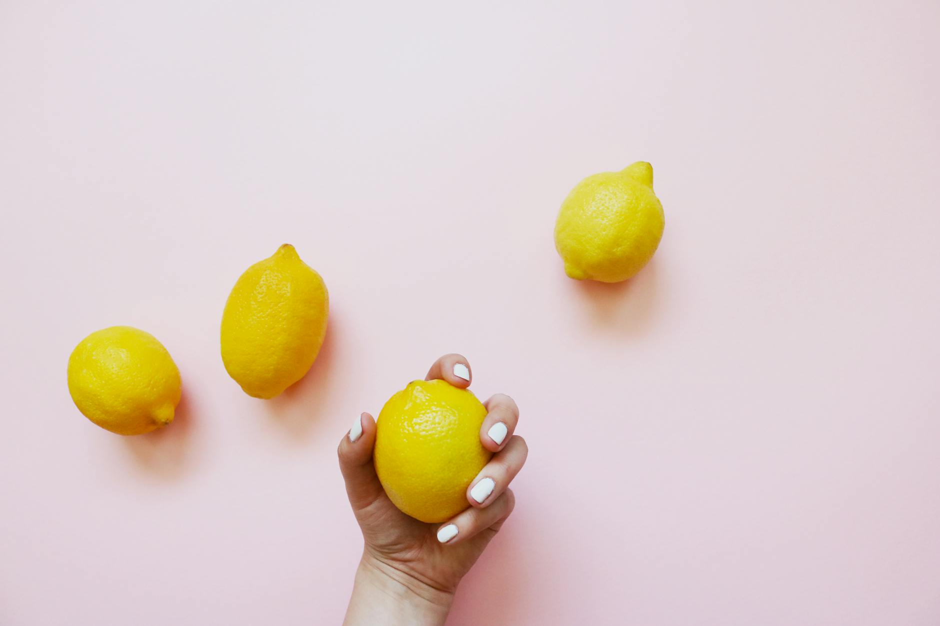 A close-up of a hand holding an orange vibrator against a minimalistic purple backdrop