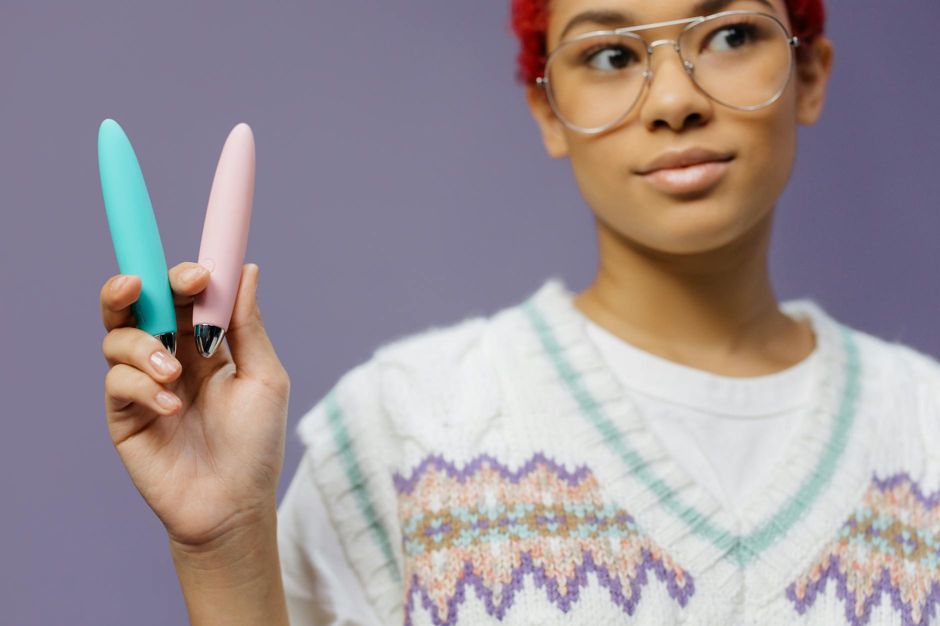 Woman holding colorful vibrators against a purple background, representing couples exploration