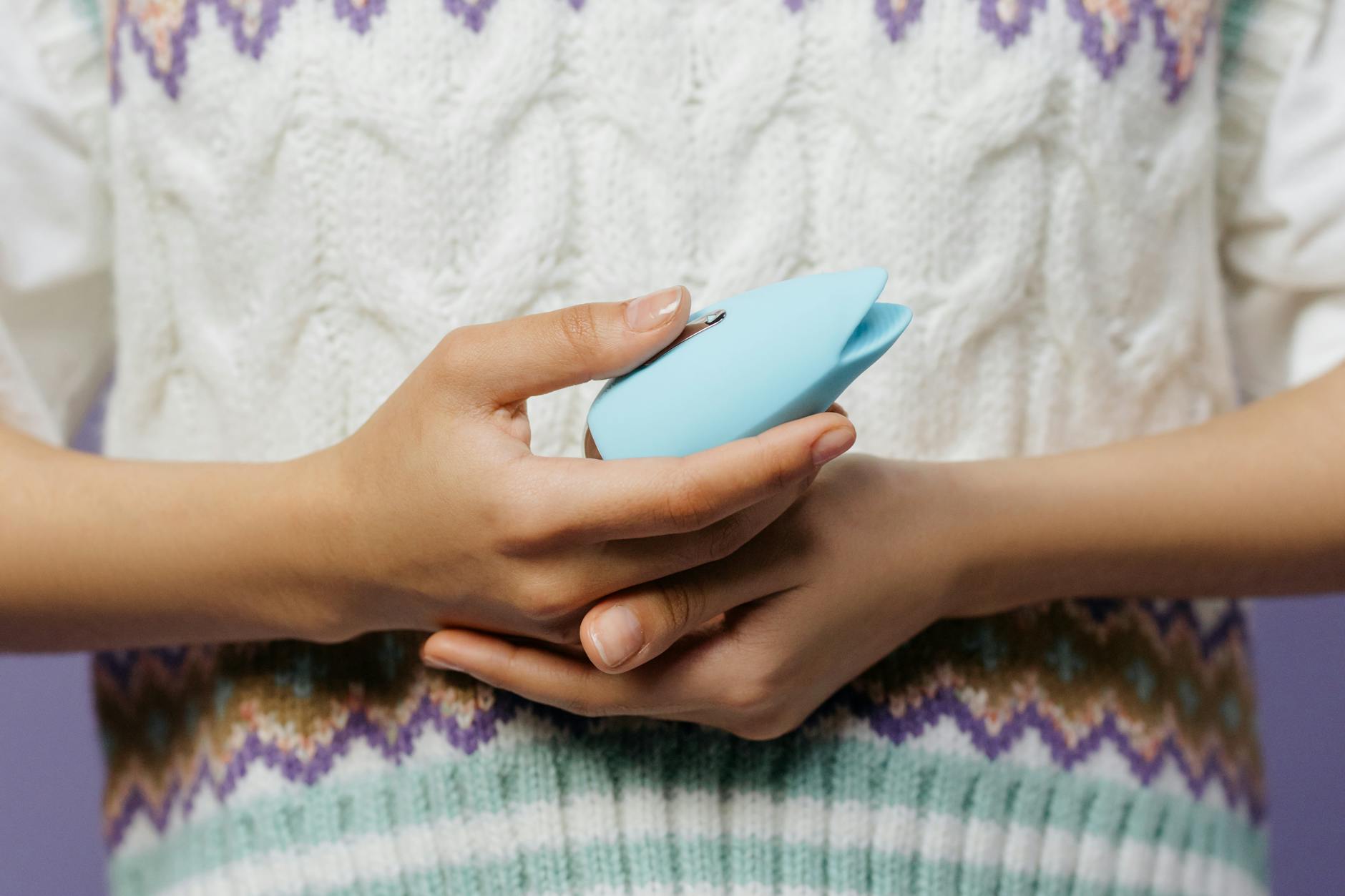 Foto di donna che tiene un vibratore personale blu contro un maglione a maglia