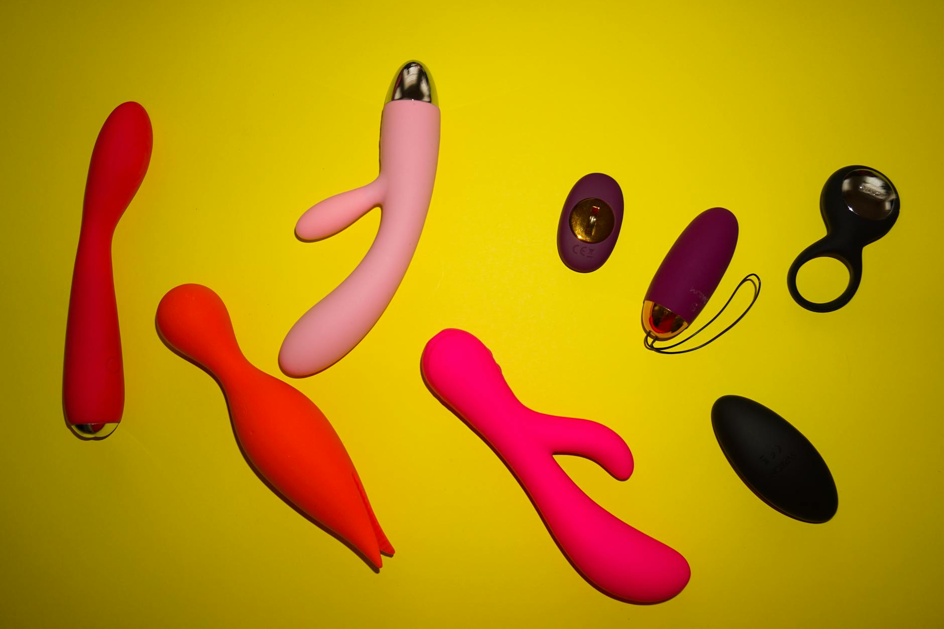 Collezione di vibratori e giocattoli intimi colorati disposti su una superficie luminosa, rappresentando la diversità e il design consapevole