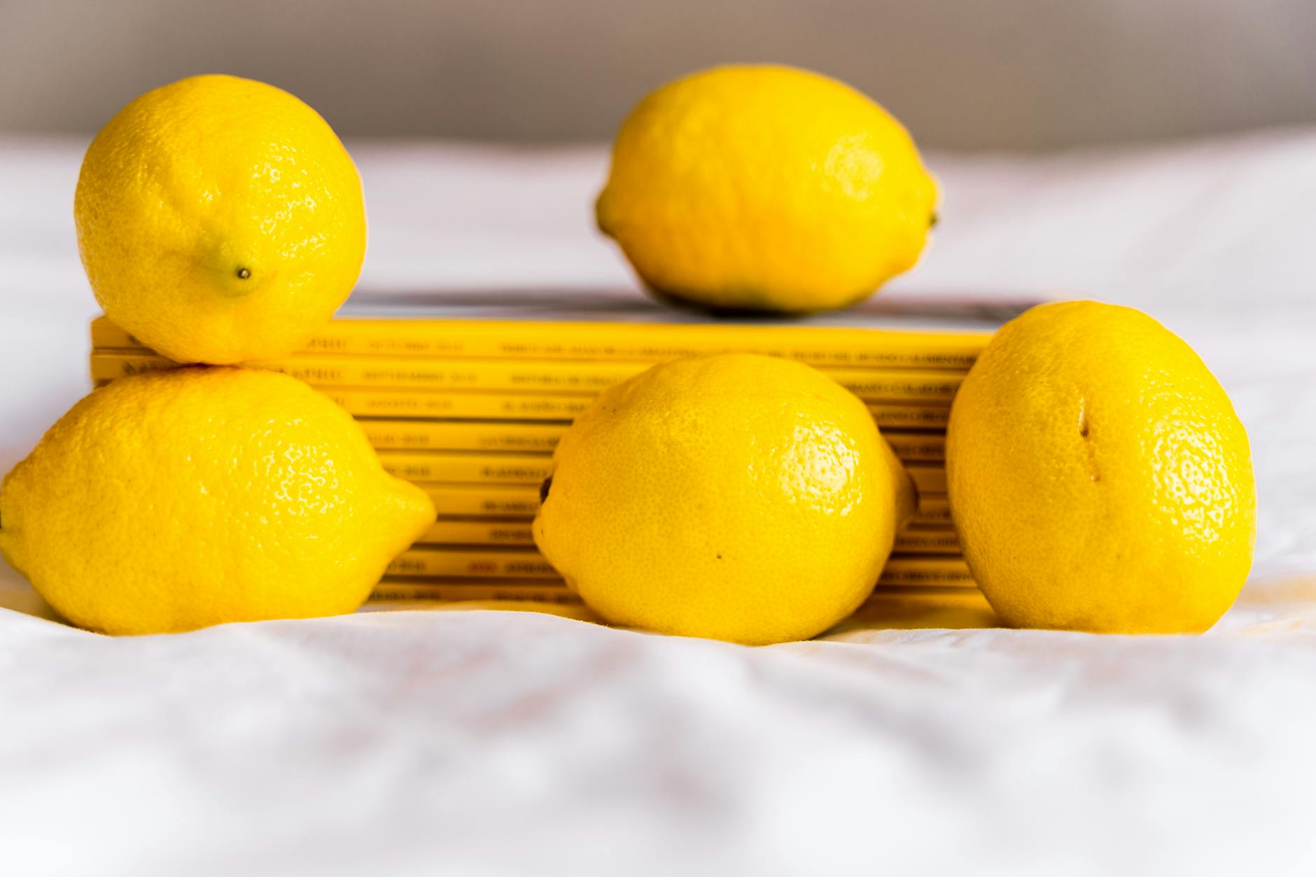 Composizione con limoni interi gialli freschi maturi e libri impilati su tovaglia bianca
